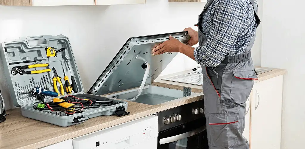 Handyman repairing a cooktop and checking wiring connections in Nashua, NH