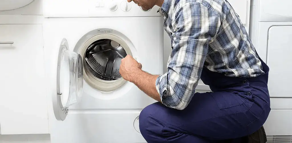 Handyman inspecting a dryer drum and internal parts for repair in Nashua, NH