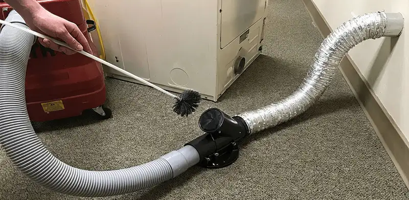 Dryer vent cleaning service removing lint from a dryer duct connection in Nashua, NH