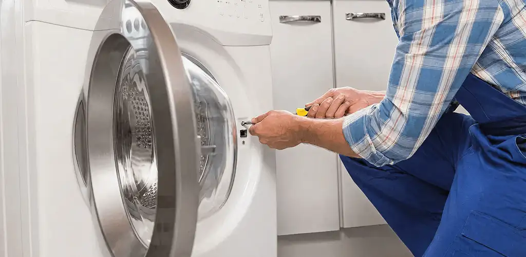Handyman repairing a clothes dryer and checking electrical connections in Nashua, NH