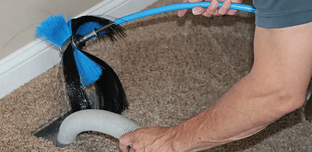 Dryer vent cleaning technician brushing lint from a vent line in Nashua, NH