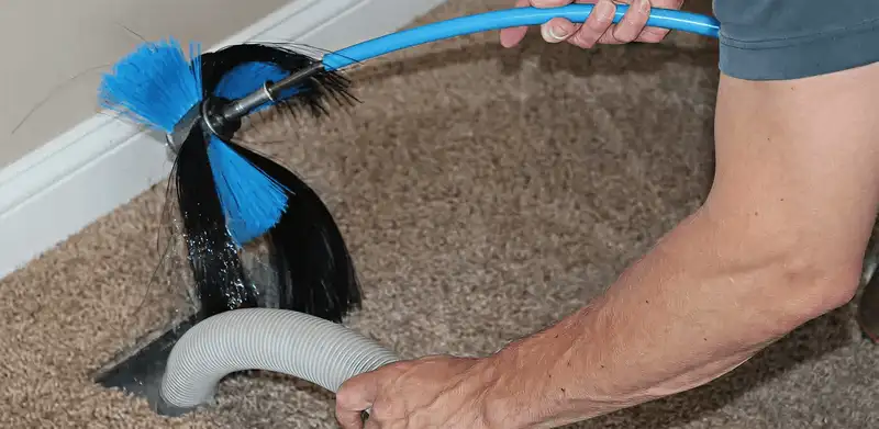 Dryer vent cleaning technician brushing lint from a vent line in Nashua, NH