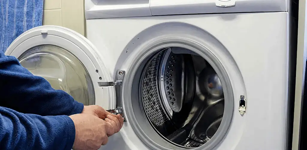 Washing machine repair handyman checking a front-load washer door and latch in Nashua, NH