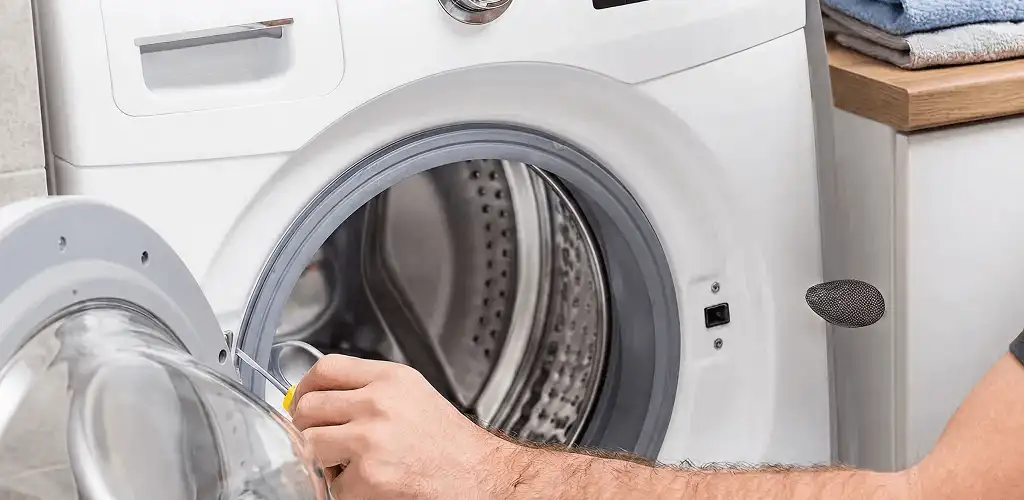 Handyman repairing a front-load washing machine and inspecting the drum in Nashua, NH