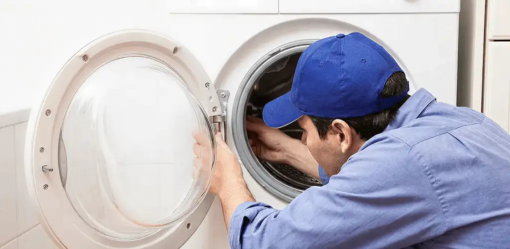 Washing machine repair handyman inspecting a front-load washer drum in Nashua, NH