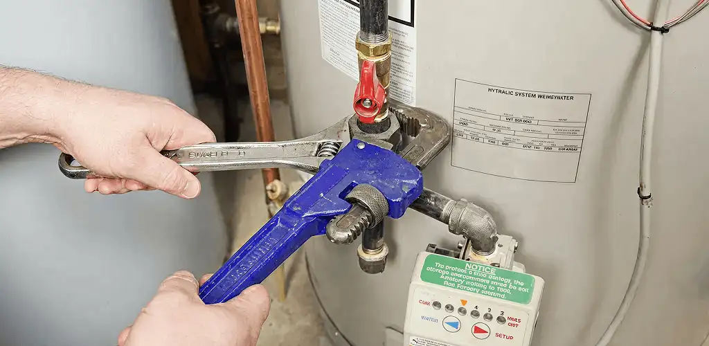 Water heater repair technician tightening the shutoff valve and supply line in Nashua, NH